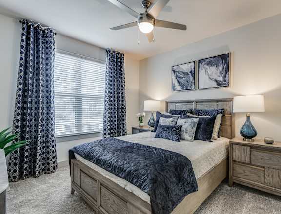 the master bedroom has a king sized bed and a ceiling fan