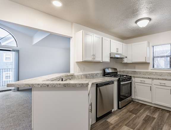 A kitchen with white cabinets and a marble countertop.