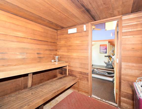 A wooden room with a bench and a doorway leading to another room.