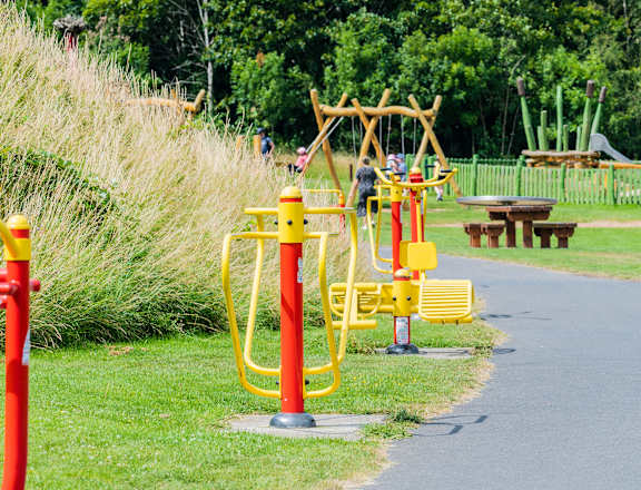 a playground with yellow and red equipment and people in the background