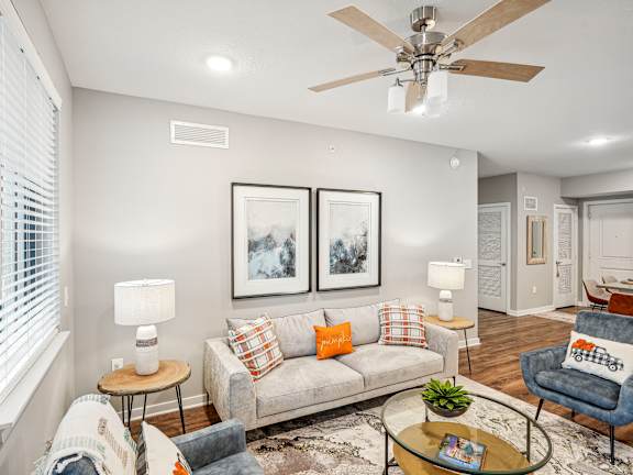 A living room with a grey couch, a blue armchair, and a coffee table at Edge75, Naples, Florida 34104