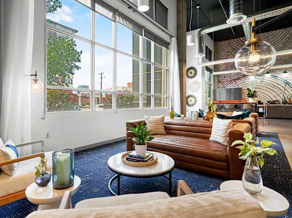 A living room with a brown couch, a white table, and a large window.