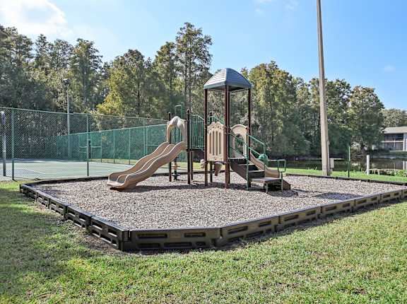 A playground with a slide and a wooden swing set.