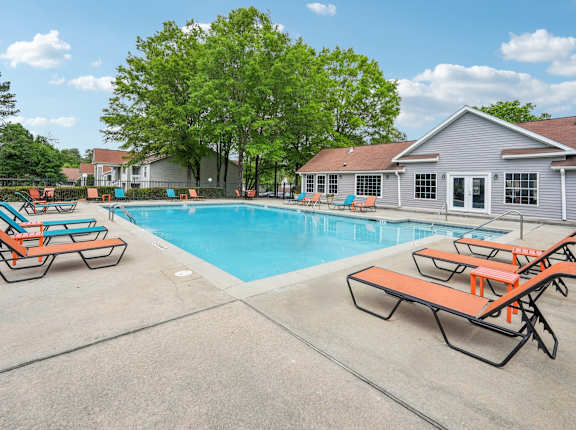 A pool with sun loungers and a house in the background.