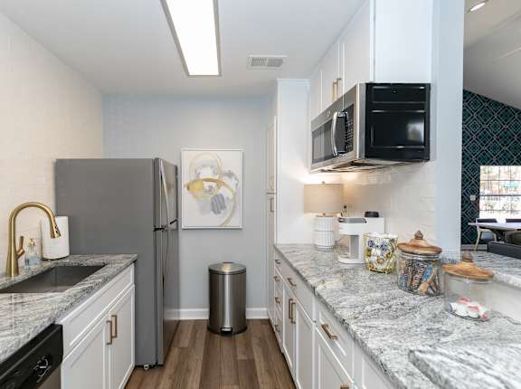 A kitchen with a marble countertop and a fridge.