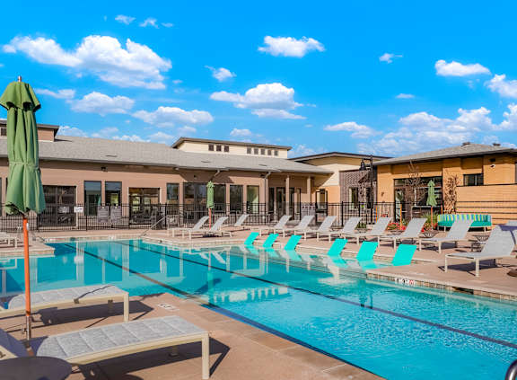 A pool with sun loungers and umbrellas in front of a building.