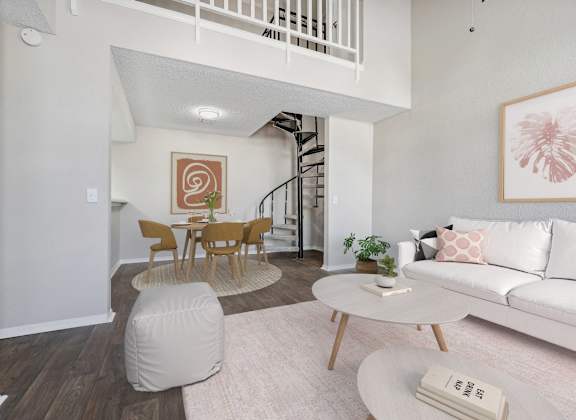 a living room with a white couch and a table and a spiral staircase