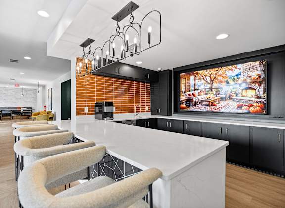 A modern kitchen with a long white island and bar stools.