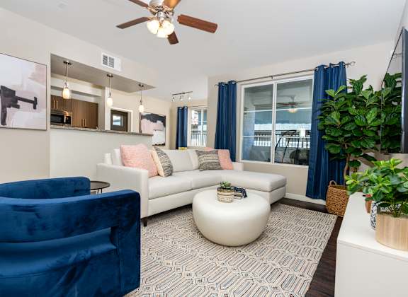 A living room with a blue velvet chair and a white sofa.
