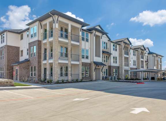 A large apartment complex with a parking lot in front.