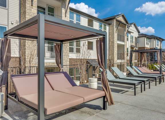 A row of sun loungers are set up in front of apartment buildings.