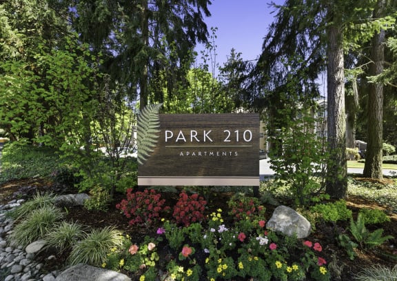 a sign that says park 201 apartments with flowers and trees in front of it  at Park 210 Apartment Homes, Edmonds, Washington