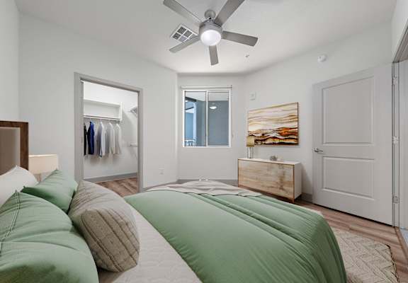 A bedroom with a bed, pillows, a dresser, and a painting on the wall.