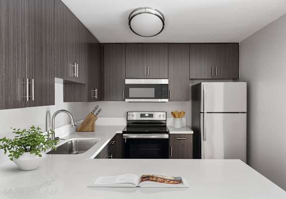 A modern kitchen with a white countertop and a stainless steel refrigerator.