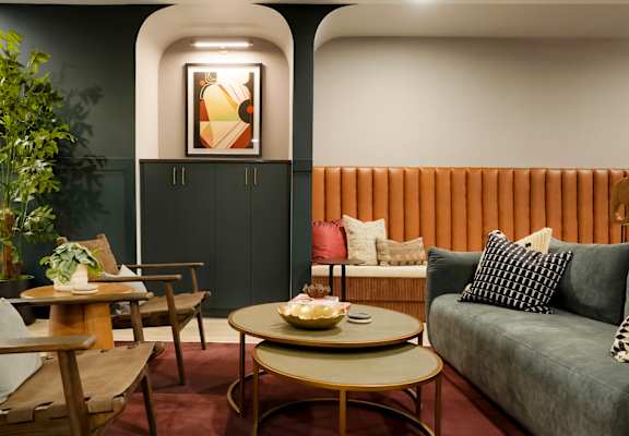A living room with a grey couch, a wooden table, and a painting on the wall.