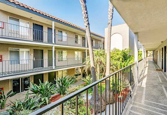 A long balcony with a metal railing and a building in the background.
