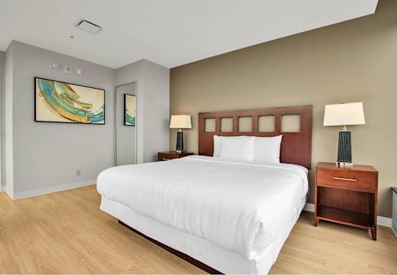 A bedroom with a large bed, two nightstands, and a painting on the wall.
