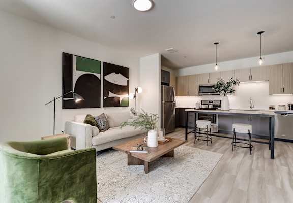 a living area with a couch coffee table and chair and a kitchen with a breakfast bar