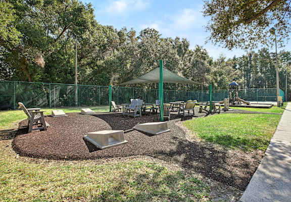 A playground with a green canopy and a fence.