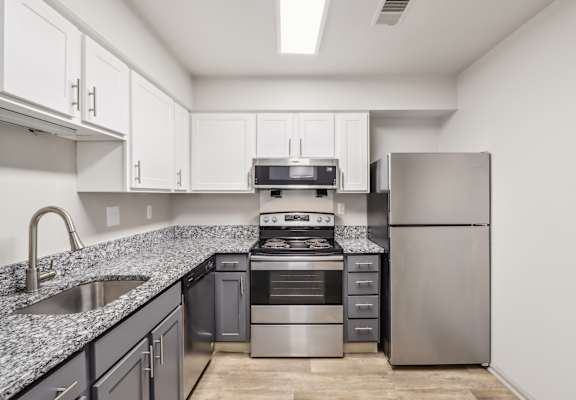 A kitchen with a stainless steel refrigerator, oven, and sink.