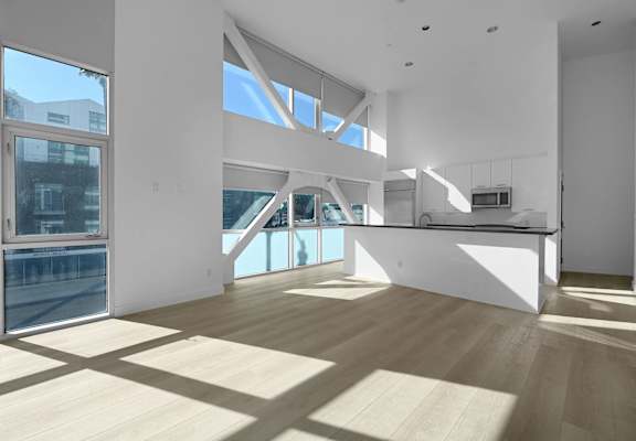 A spacious, well-lit room with wooden floors and large windows.