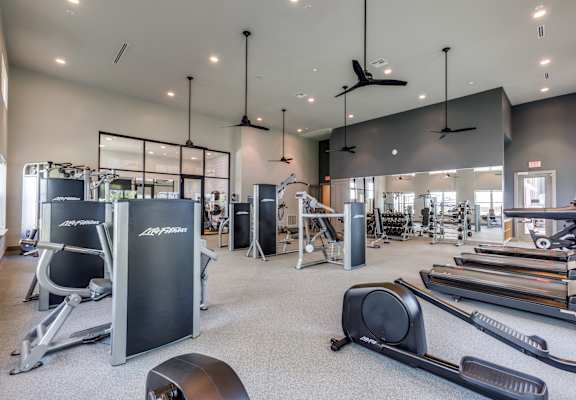 A gym with a variety of equipment including treadmills, weights, and exercise machines.