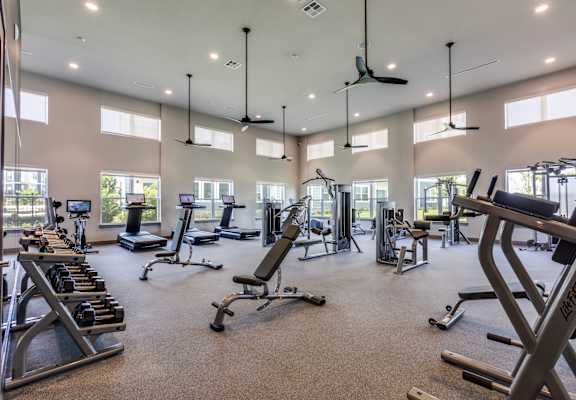A spacious gym with a variety of equipment and a ceiling fan.