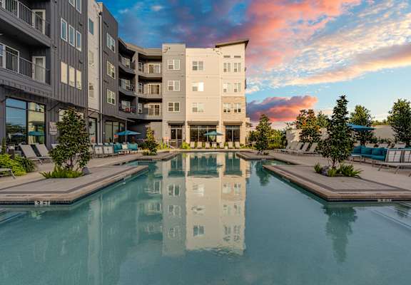 A large building with a pool in front of it.