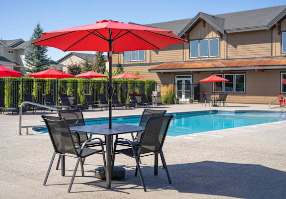A red umbrella is in the foreground of a pool area.