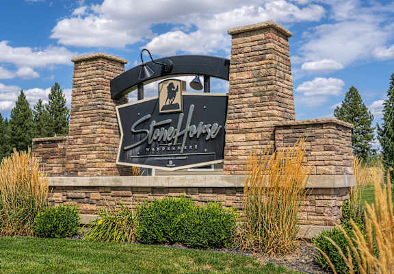 A sign for Stables Ranch Wanderers stands in front of a stone wall.