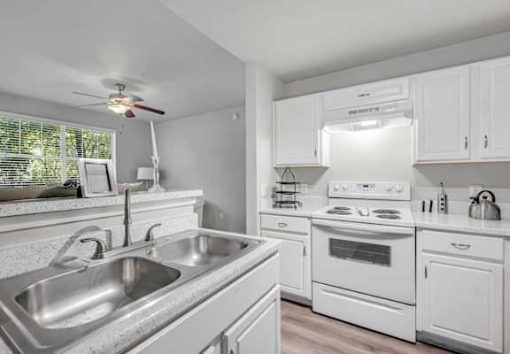 a kitchen with a sink and a stove and a ceiling fan at Villas of Sorrento Apartments, Dallas