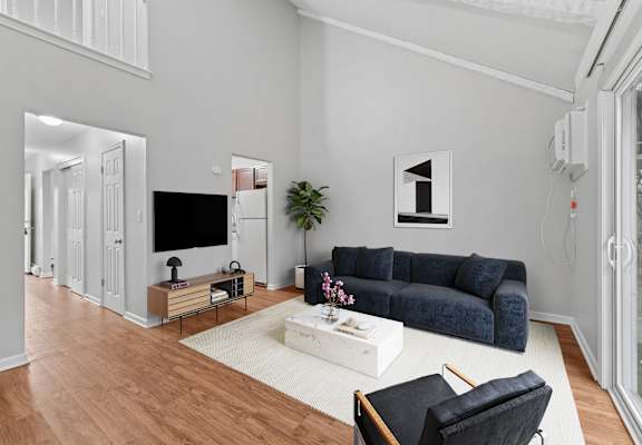 A living room with a blue couch, a white coffee table, and a television.