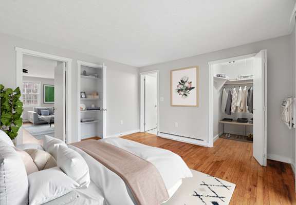 A bedroom with a bed, a couch, a wardrobe, and a plant.