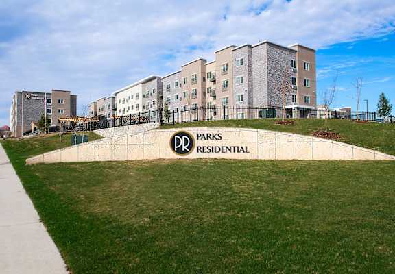 a retaining wall with a sign in front of some apartments at Parks Residential - Richardson, Richardson, 75082