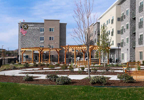 a courtyard with benches and a building with an flag at Parks Residential - Richardson, Richardson, 75082