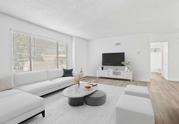 A modern living room with a white sofa, a grey coffee table, and a flat-screen TV.