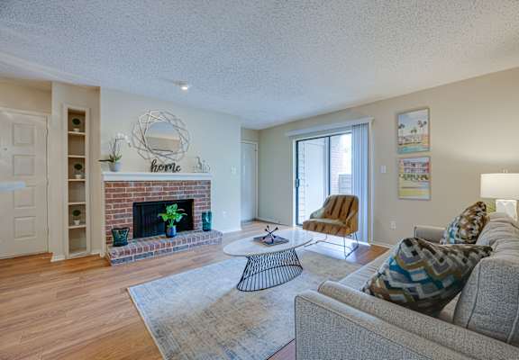 a living room with a fireplace and a sliding glass door at Indian Creek Apartments, Carrollton, TX