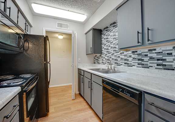 an empty kitchen with a sink and a refrigerator at Indian Creek Apartments, Carrollton, Texas