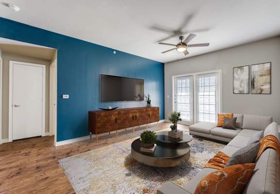 a living room with a blue accent wall and a couch and a tv  at Valor at Harlingen, Harlingen, Texas