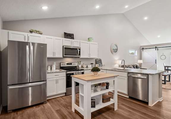 A kitchen with a wooden table and stainless steel appliances.