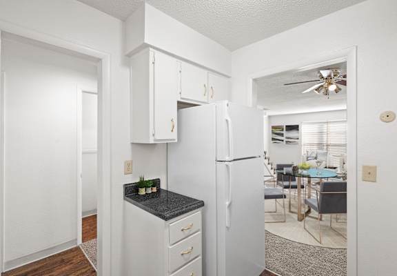 A kitchen with a refrigerator, cabinets, and a dining table.