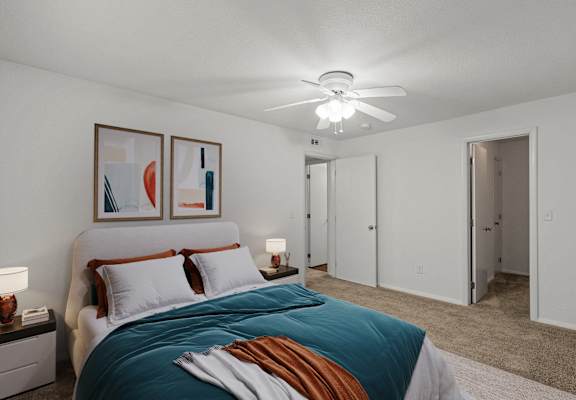 A bedroom with a bed, two lamps, and two framed artworks on the wall.