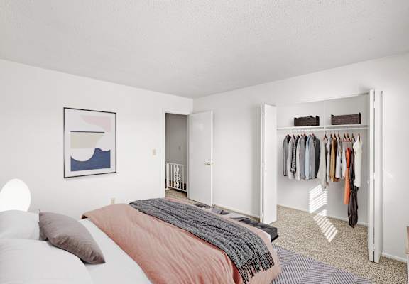 A bedroom with a bed, a closet, and a painting on the wall.