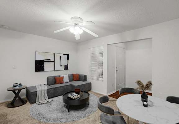 A living room with a grey couch, a coffee table, and a ceiling fan.