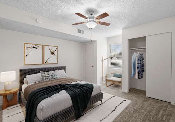 A bedroom with a bed, a ceiling fan, and a wardrobe.