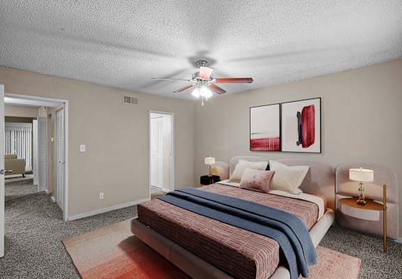 A bedroom with a bed, a nightstand, and a ceiling fan.