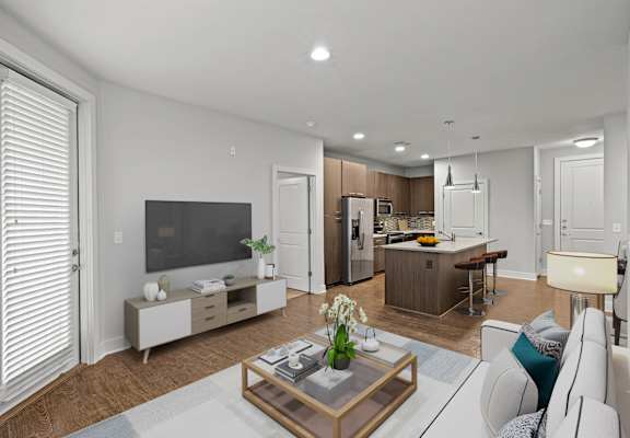 A modern living room with a flat screen TV, a coffee table, and a kitchen area in the background.