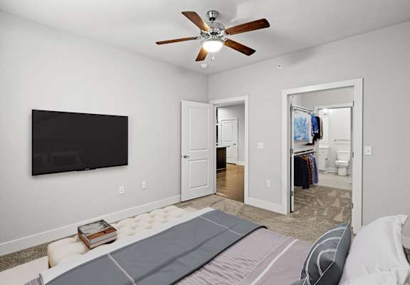 A bedroom with a bed, a ceiling fan, and a television.