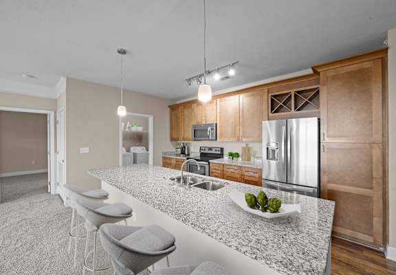 A kitchen with a granite countertop and bar stools.