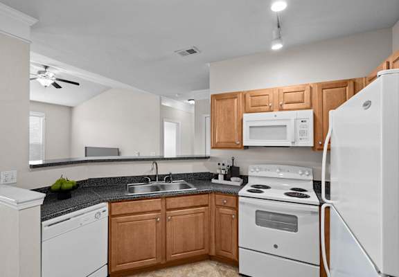 A kitchen with white appliances and wooden cabinets.